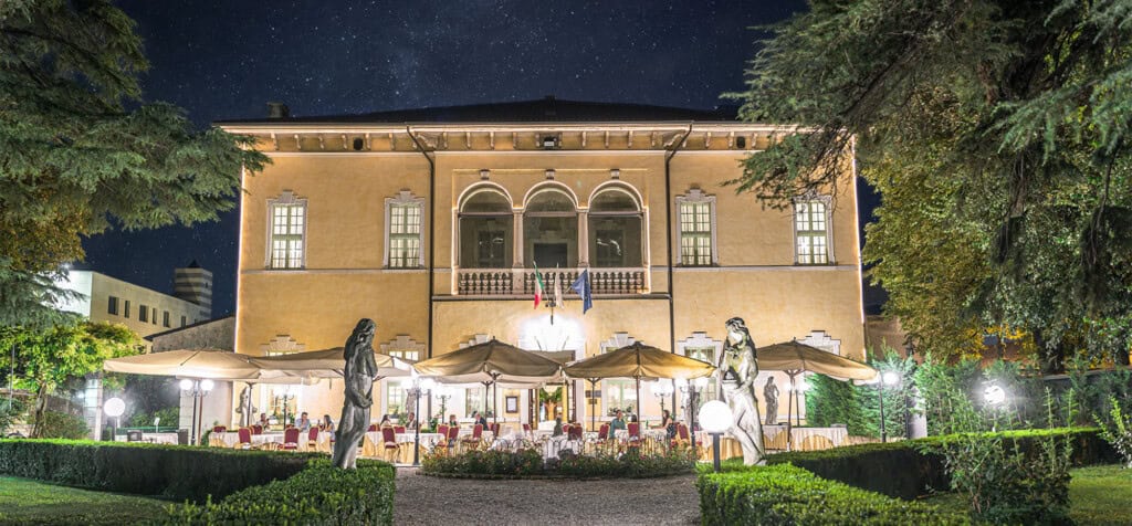 Restaurang i Italien kvällstid med härlig grönska runt uteplatserna.